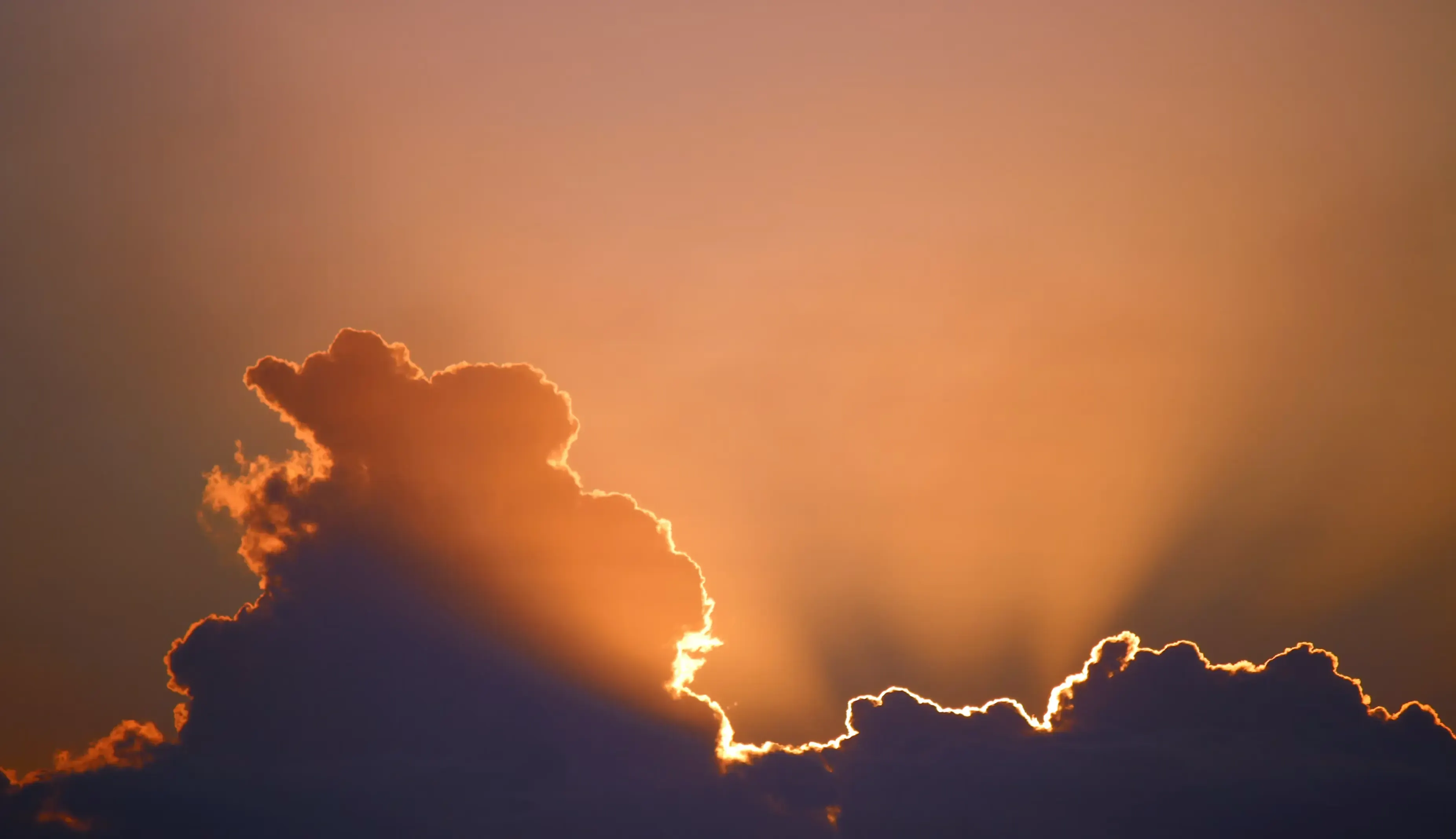 The sun on the horizon over the sea, under a sky ablaze with red and orange.