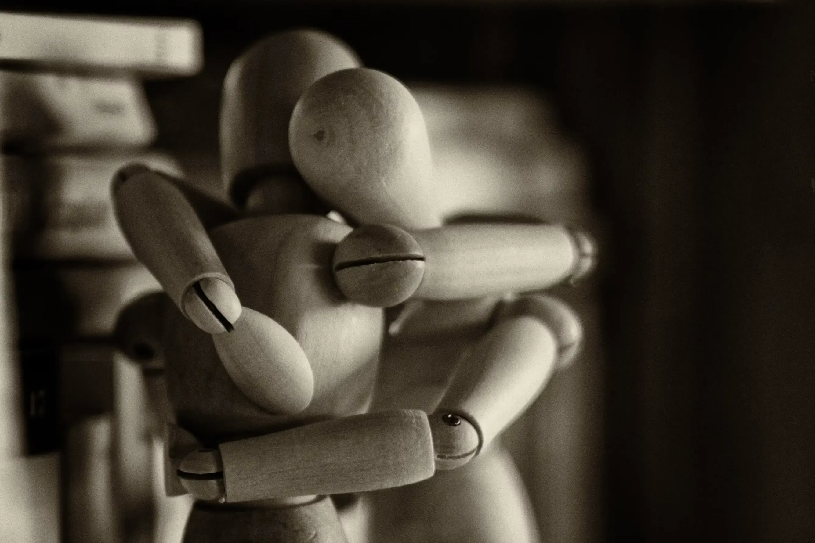 Two articulated wooden figures locked in an embrace.